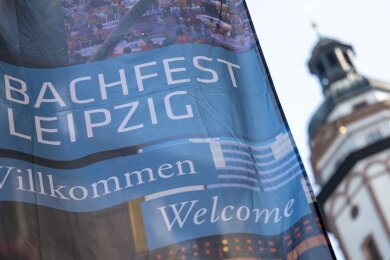 Ein Fahne des Bachfests Leipzig weht neben dem Turm der Thomaskirche.