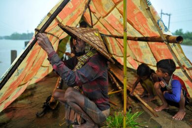 Hochwasser in Bangladesch: Eine Familie stellt ein Zelt auf, um sich vor den Wassermassen zu schützen. Durch anhaltende Regenfälle und Erdrutsche ist die Region um Sylhet in Bangladesch überflutet.