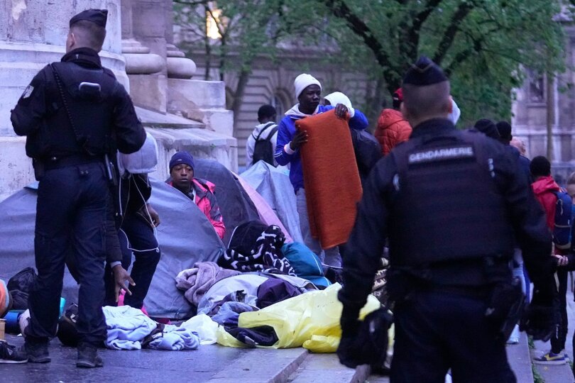 Polizisten vertreiben Migranten aus einem behelfsmäßigen Lager in Paris. Ähnliche Aktionen werden von den Polizeibehörden in den Monaten vor den Olympischen Spielen täglich durchgeführt.