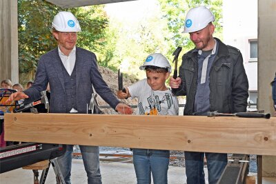 Zum Richtfest wird gehämmert: Baubürgermeister Michael Stötzer, Grundschüler Florian und Schulleiter Lars Ritter (v. l.) greifen zum Werkzeug.