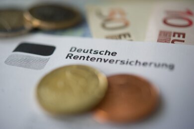 Geld liegt neben einem Schreiben mit der Aufschrift "Deutsche Rentenversicherung".