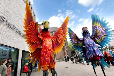 Zwei Papagei-Statuen stehen für die Eröffnungsparade des Figurentheaterfestivals Fidena in Bochum auf der Straße. Mit übergroßen Insekten und seltsamen Lebewesen wurde ein Statement gegen das Artensterben gesetzt.