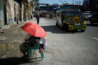 Extreme Hitze in den Straßen von Manila: Eine Verkäuferin schützt sich mit einem Regenschirm vor der Sonne. Auf den Philippinen und in weiteren südostasiatischen Ländern herrschen Rekordtemperaturen von gefühlt über 50 Grad.