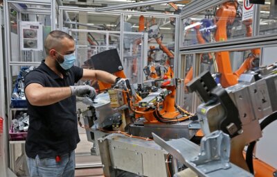 80 Roboter für E-Autos laufen sich warm - Bediener Adnan Alhallak beim Einlegen der zu bearbeitenden Teile in eine der vier Fügeanlagen. 