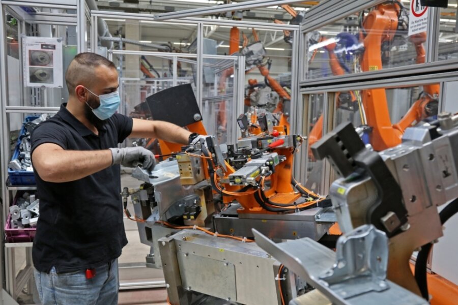 80 Roboter für E-Autos laufen sich warm - Bediener Adnan Alhallak beim Einlegen der zu bearbeitenden Teile in eine der vier Fügeanlagen. 