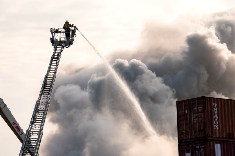Rauch über der Stadt: Ein Schrotthaufen auf einem Firmengelände am Hamburger Hafen ist in Brand geraten.