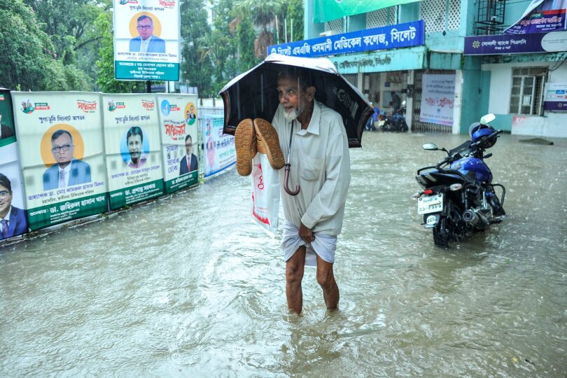 Hochwasser in Bangladesch: Um zum Krankenhaus zu gelangen, muss ein Patient durch Wassermassen waten. Aufgrund anhaltender Regenfälle sind die Straßen in Sylhet überflutet worden.