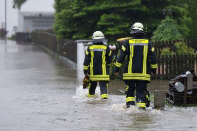 Feuerwehrleute waten in Dasing im schwäbischen Landkreis Aichach-Friedberg durch eine überflutet Straße. In den Überschwemmungsgebieten im Süden Deutschlands werden die Evakuierungsaufrufe der Behörden angesichts steigender Flusspegel ausgeweitet.