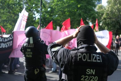 Polizisten setzen bei einer linken Demonstration Schutzhelme auf.