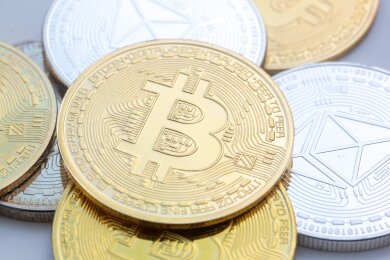 Bitcoin (M) und Ethereum-Münzen sind auf einem Tisch angeordnet.