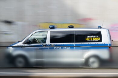 Ein Polizeiauto mit der Aufschrift "Verdächtig gute Jobs!" fährt eine Straße entlang.