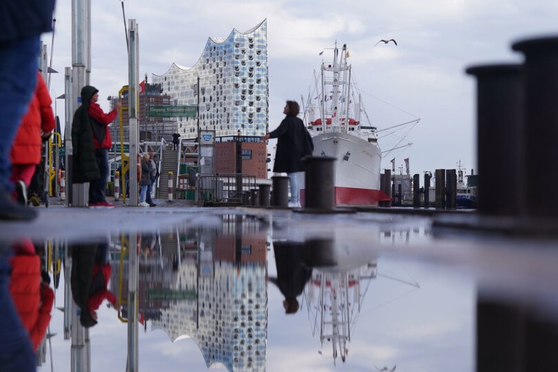 Die Elbphilharmonie spiegelt sich an den Landungsbrücken im Hamburger Hafen.