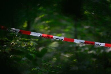 Absperrband der Polizei ist in einem Wald gespannt. In einem Waldstück bei Döbeln wurde die Leiche der vermissten neunjährigen Valeriia gefunden.