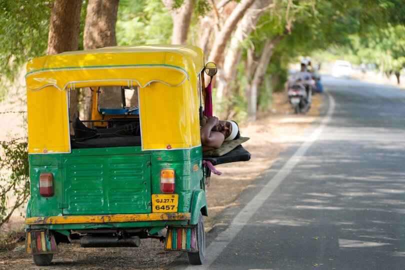 Ein Auto-Rikscha-Fahrer ruht sich an einem heißen Sommertag in seinem Fahrzeug aus, das im Schatten eines Baumes bei der Stadt Ahmedabad geparkt ist. Noch immer ist Indien von einer Hitzewelle betroffen.