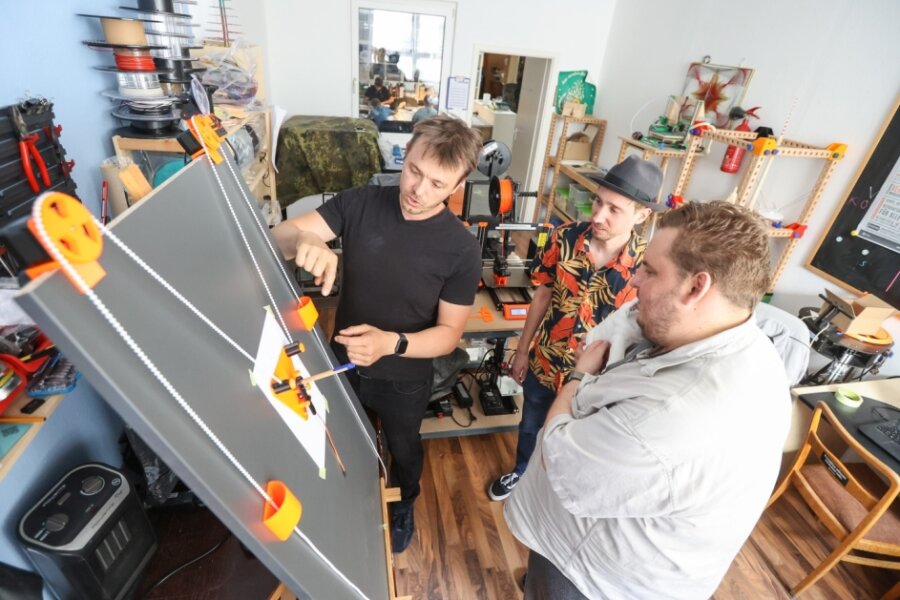 Marcel Spranger erklärt Benjamin Schürer und Daniel Tauscher (von links) , die zum Team des Fablab gehören, den in der Endfertigung befindlichen Prototypen einer von Software gesteuerten Zeichenmaschine
