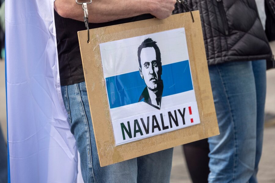 Alexej Nawalny bekommt posthum Dresdner Friedenspreis - Ein Mann trägt ein Schild mit dem aufgedruckten Gesicht von dem gestorbenen Regimegegner Alexej Nawalny.