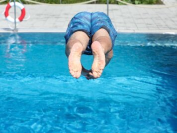            Ein Mann springt von einem Sprungbrett kopfüber ins Wasser.