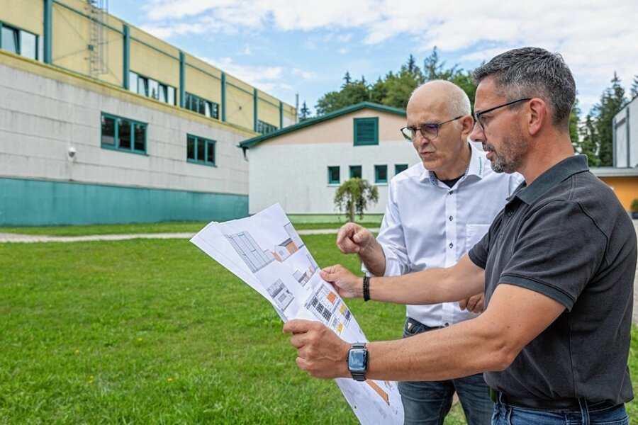 Waldpark-Geschäftsführer Joachim Otto (hinten) und Sören Voigt, Präsident des Landesverbandes Kinder- und Jugenderholungszentren Sachsen, checken den Bauplan für den Anbau des Funktionsgebäudes. 