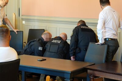 Angeklagter im Mordprozess rastet aus: Rettungshubschrauber vor dem Landgericht Zwickau - Der Angeklagte liegt am Boden, Beamte beugen sich über ihn. Sie halten ihn fest, bis der Notarzt kommt.
