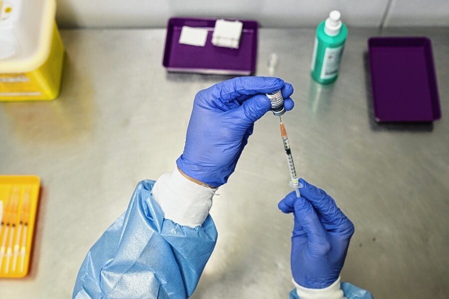 In einem Impfzentrum wird eine Spritze mit dem an die Omikron-Variante angepassten Corona-Impfstoff aufgezogen. 