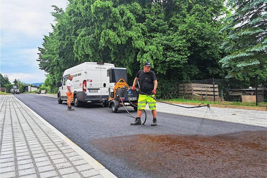 Arbeiten an Zschopauer Luxemburg-Straße schreiten voran - Auf die Tragschicht spritzen Arbeiter ein Bindemittel auf, damit die Deckschicht besser hält.