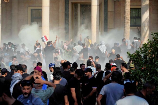 Atempause im Machtkampf: Steuert der Irak auf einen neuen Bürgerkrieg zu? - In Tränengaswolken gehüllt, protestieren Anhänger des Schiitenführers Muktada al-Sadr vor dem Regierungspalast in Bagdad. Sadr rief seine Gefolgsleute inzwischen von der Straße zurück. 
