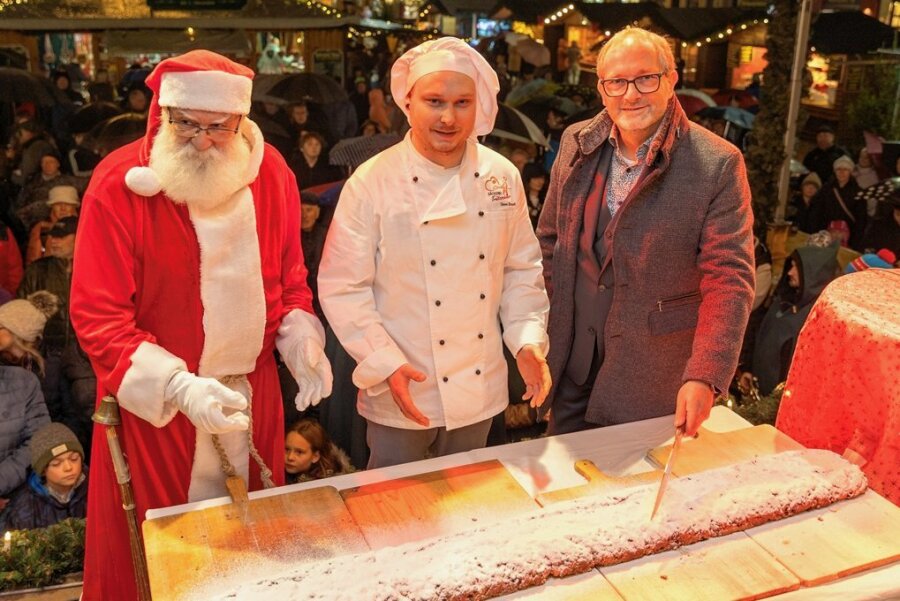 Auerbachs Oberbürgermeister und der Weihnachtsmann schneiden Stollen an - Auerbachs OB Jens Scharff hat am Freitagabend zusammen mit Bäckermeister Steve Brasch (Mitte) und dem Weihnachtsmann angeschnitten.