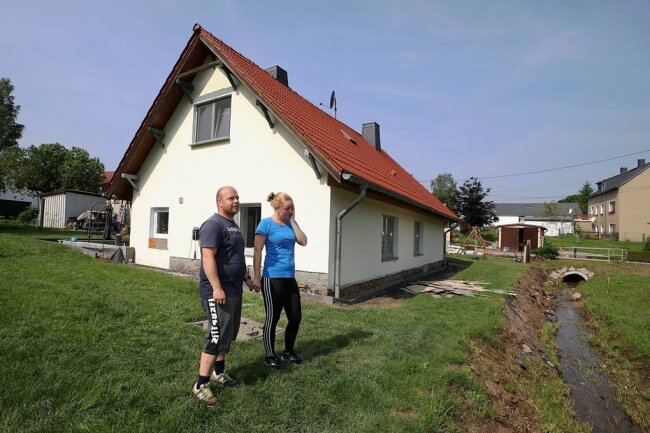 Jasmin Maibach und Benjamin Gottschling stehen vor ihrem Haus, das sie aufgrund der Schäden im Erdgeschoss verlassen mussten. 