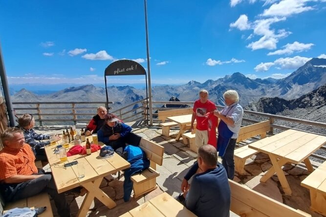 Auf der mit neuen Holztischen und -bänken ausgestatteten Terrasse der Zwickauer Hütte vor dem herrlichen Alpenpanorama.