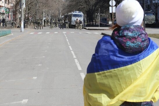Eine Frau mit ukrainischer Fahne steht bei einer Demonstration gegen die russische Besatzung in Cherson. 
