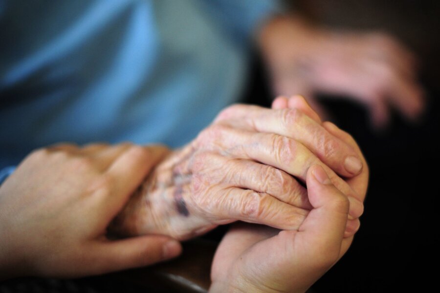 Ausländerbeauftragter lobt Zuwanderung von Pflegekräften - Eine Pflegekraft hält in einem Seniorenheim die Hand einer Bewohnerin.