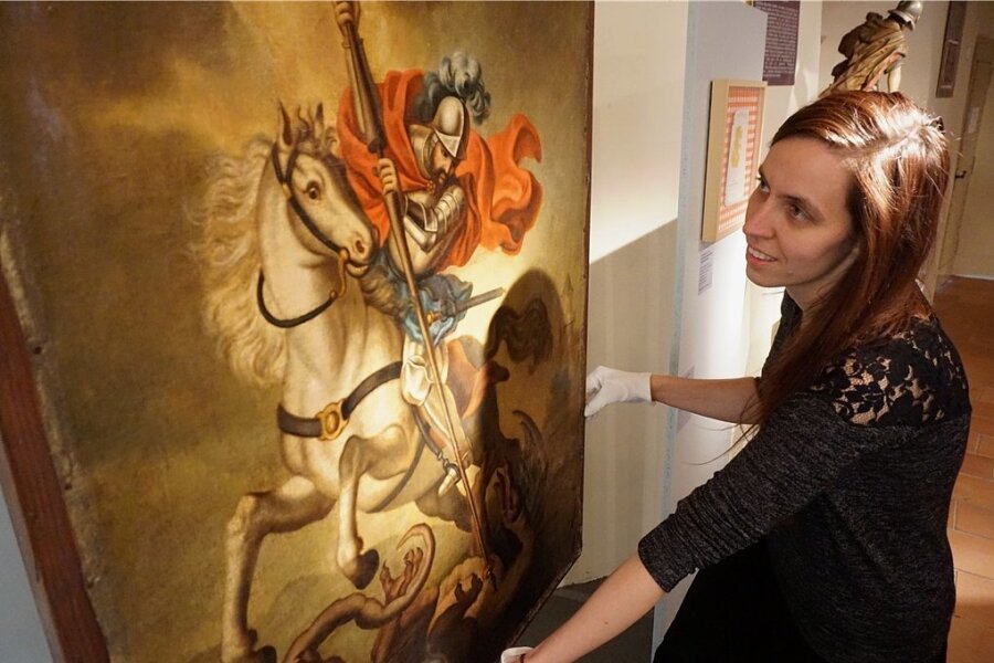 Museumsleiterin Tina Reitz mit einem Ölgemälde mit dem Motiv des Heiligen Georgs und dem Drachenstich.