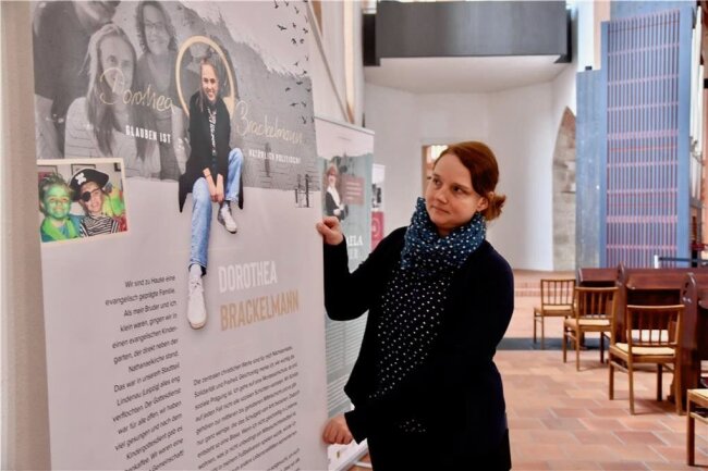 Ausstellung in Chemnitz: Wie schauen Frauen heute auf entscheidende Stationen ihres Lebens zurück? - Sabine Winkler vom Evangelischen Forum in der Ausstellung am Plakat, das die Biografie von Dorothea Brackelmann dokumentiert, einer Frau, die 2020 für die Schau interviewt wurde, als sie in Leipzig lebte. 