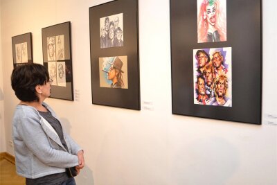 Ausstellung in Meerane: Rock- und Popstars aufs Korn genommen - Eine Besucherin schaut auf die „Karockaturen“ von Johannes Sauer im Meeraner Kunsthaus.
