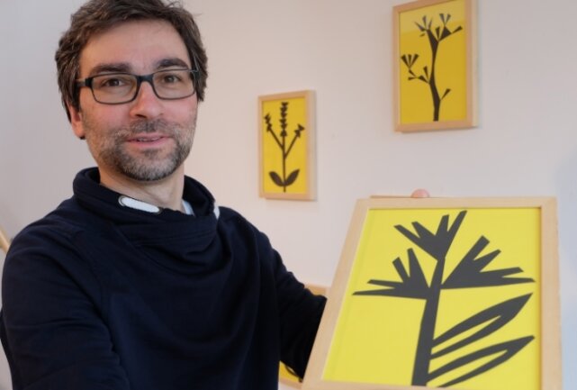 Galerieleiter Alexander Stoll mit Papierschnitten zum Thema "Jöhstadtveilchen" von Katja Schwalenberg. 