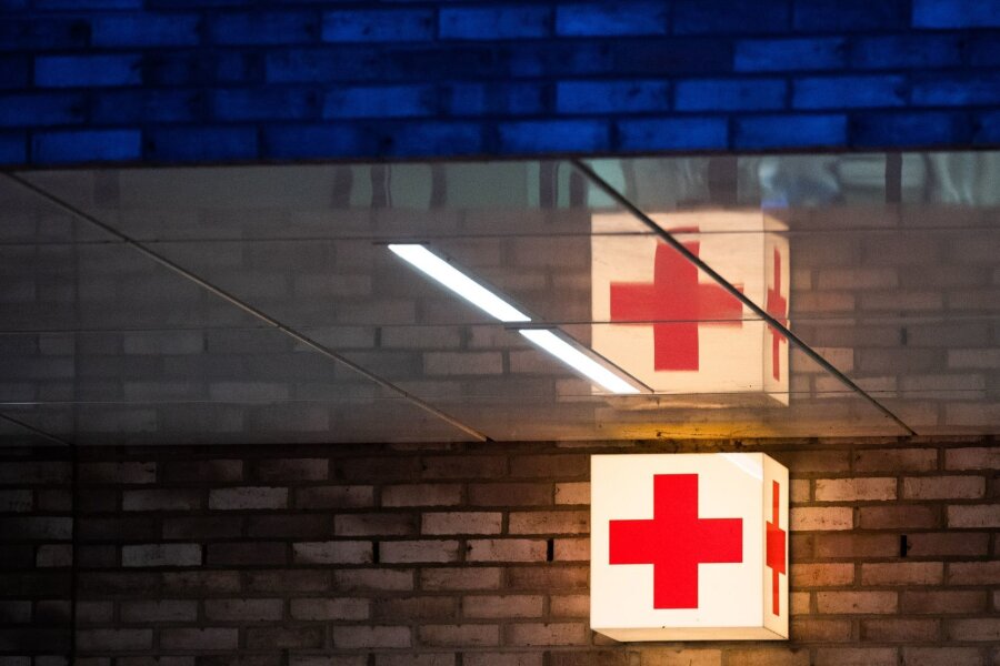 Auto schleudert gegen Leitplanke: Elfjährige schwer verletzt - Ein Leuchtkasten mit einem roten Kreuz hängt vor der Notaufnahme eines Krankenhauses.