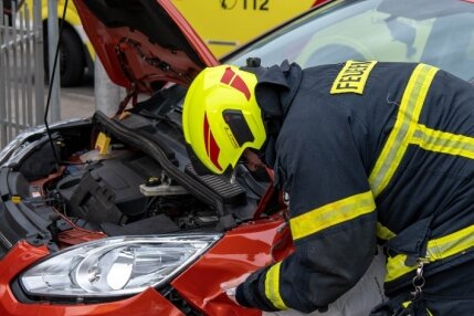 Autos in Rochlitz kollidiert - Ein Feuerwehrmann bindet ausgelaufene Schadstoffe des im Unfall verwickelten Pkws (Ford).