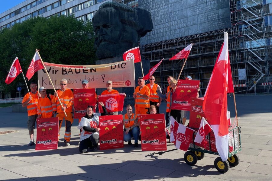Bauarbeiter streiken in Chemnitz für mehr Lohn - Vor ihrem Umzug durch die Innenstadt haben sich die streikenden Bauarbeiter vor dem Karl-Marx-Monument aufgestellt.