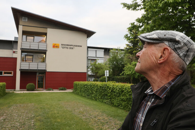 Der 84 Jahre alte Rentner Alfons Blum steht vor dem Seniorenpflegeheim Otto Dix. In diesem Heim wohnt seine Ehefrau. Er gab am 16.05.2020 bei einer Anti-Corona-Demo ein bewegendes Interview, da er seit mehreren Wochen seine Frau Gisela wegen der Corona-Einschränkungen nicht mehr sehen kann. 