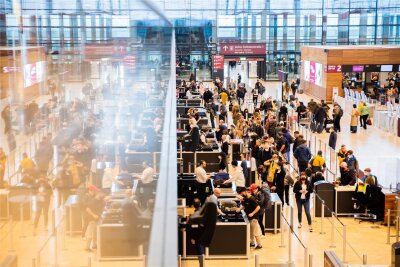 Beliebtheitscheck: So bewerten Passagiere die Flughäfen in Sachsen - Passagiere stehen am Flughafen Berlin Brandenburg "Willy Brandt" (BER) vor der Sicherheitskontrolle Schlange.