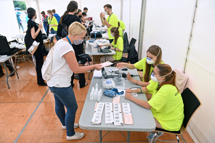 Eine Probandin (vorne, links) steht vor Beginn eines Großversuchs der Universitätsmedizin Halle/Saale am Check-In.