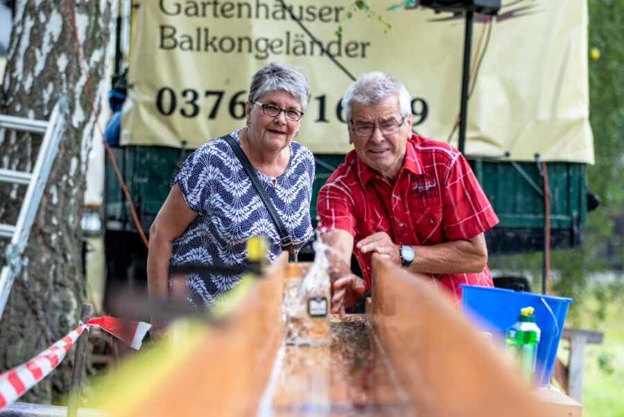Bierrutsch-Premiere beim Teichfest in Dürrengerbisdorf: Eisstockschießen mit Bierkrügen - Dietmar Groß aus Pleißa versucht sich an der "Bierrutsche" beim Teichfest im Limbach-Oberfrohnaer Ortsteil Dürrengerbisdorf. Der 71-Jährige ist mit seiner Lebensgefährtin bereits zum wiederholten Mal zu Gast bei der Veranstaltung. Bei dem Spiel muss ein gefüllter 1-Liter-Maßkrug auf einer zehn Meter langen, mit Seifenwasser benetzten Holzbahn so weit wie möglich geschoben werden, ohne dass das Glas am Ende zu Boden stürzt. Gewonnen hat, wer der Zehnmetermarke am nächsten kommt. Dietmar Groß schaffte am Samstagnachmittag mit 9,71 Meter bereits einen beachtlichen Wert.