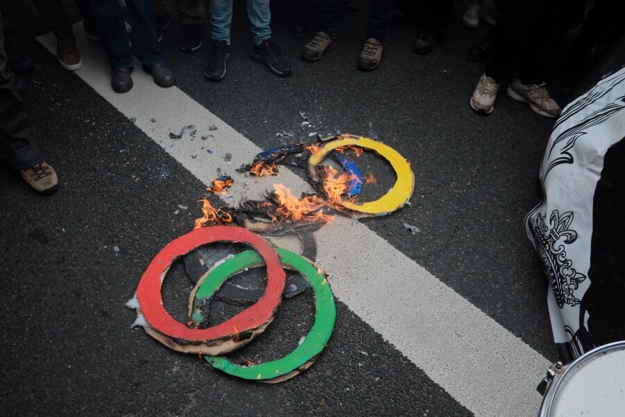 Bilder des Tages vom 01.05.2024 - Mit brennenden Ringen machen einige Pariser am 1. Mai darauf aufmerksam, was sie wirklich von der Ausrichtung der Olympischen Spiele in ihrer Stadt halten.