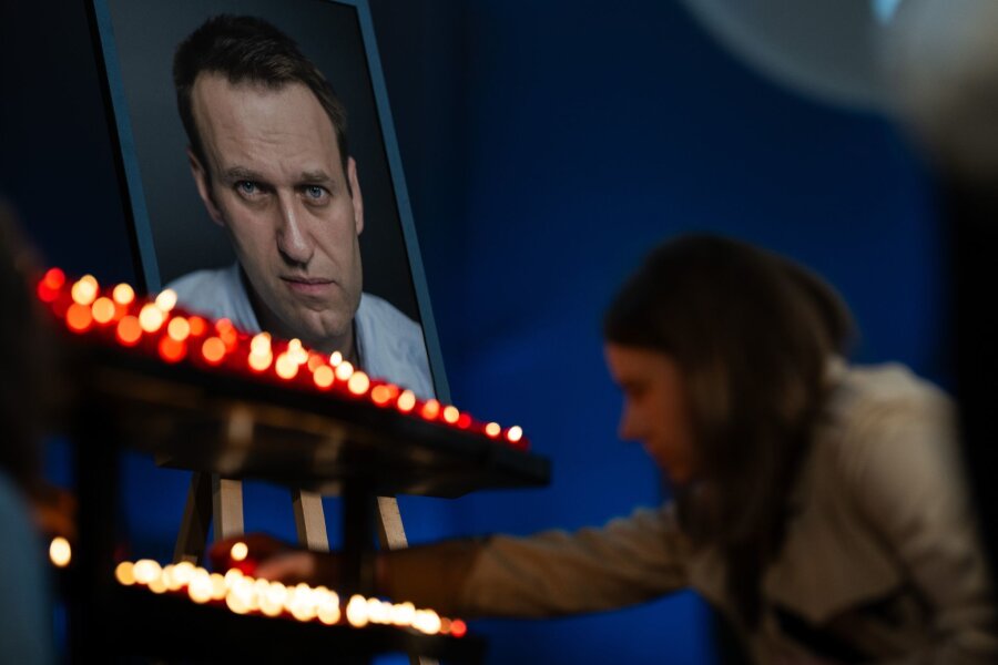 Bilder des Tages vom 04.06.2024 - Ein Gottesdienst zum Geburtstag: Eine Besucherin zündet vor dem Bild des verstorbenen Oppositionspolitiker Nawalny eine Kerze an. Er ist im Februar in einem russischen Straflager ums Leben gekommen.