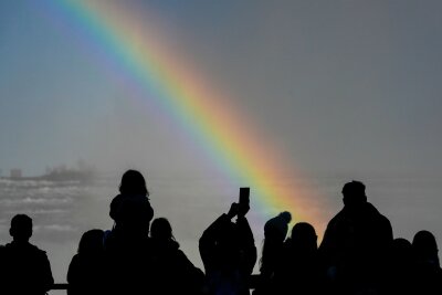 Bilder des Tages vom 08.04.2024 - Naturschauspiel: Menschen betrachten einen Regenbogen an den Niagarafällen in Kanada.