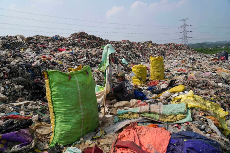 Bilder des Tages vom 10.05.2024 - Einblick in die Umweltverschmutzung der Erde: In der Deponie in Depok am Rande von Jakarta türmt sich der Müll. Für diesen Lumpensammler, der sich ausruht, gehört der Anblick zum Alltag.