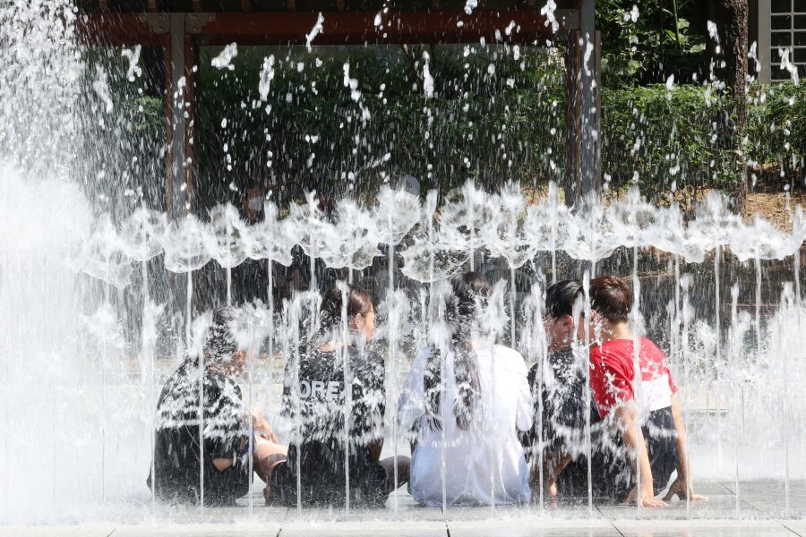 Bilder des Tages vom 10.06.2024 - In Südkorea herrscht eine Hitzewelle. Um kühlen Kopf zu bewahren, erfrischen sich diese Schülerinnen und Schüler kurzerhand in einem Brunnen.