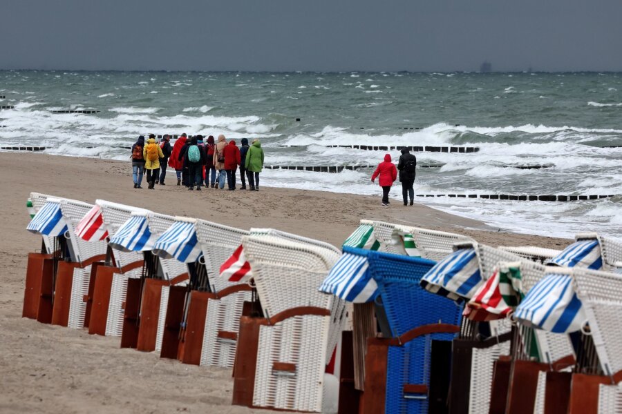 Bilder des Tages vom 11.06.2024 - Trotz Wind und Wetter: Eine Wandergruppe ist an der aufgewühlten Nordsee bei Graal-Müritz unterwegs. Im Norden Deutschlands lässt der Sommer noch auf sich warten.