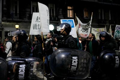 Bilder des Tages vom 13.04.2024 - Polizisten gehen neben Demonstranten, die gegen die Politik des argentinischen Präsidenten Milei protestieren.
