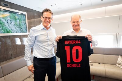 Bilder des Tages vom 15.04.2024 - Bayer-CEO Bill Anderson (l.) überreicht Bundeskanzler Olaf Scholz (SPD) ein signiertes Trikot des neuen Bundesliga-Meisters Bayer Leverkusen.